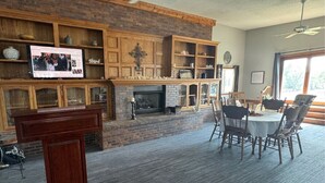Ein Wohnzimmer mit Kamin, Holzböden, einem Fernseher und einem Essbereich mit Stühlen und Tisch.