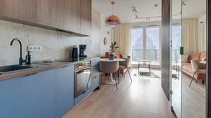 Una cocina moderna con encimera de mármol, horno integrado y una zona de comedor con mesa redonda y sillas.