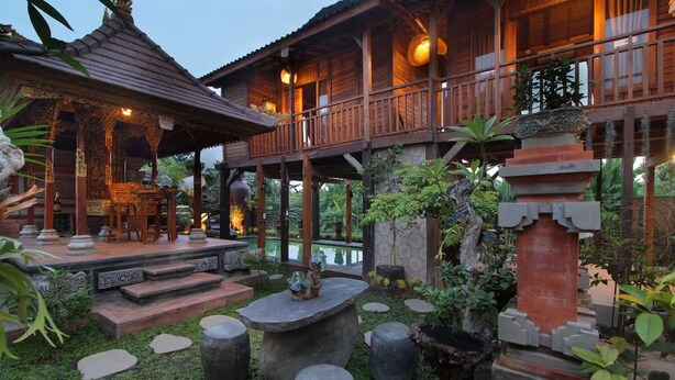 A wooden structure with a covered porch and a pool area. - Tri Datu Palace (Sukawati)