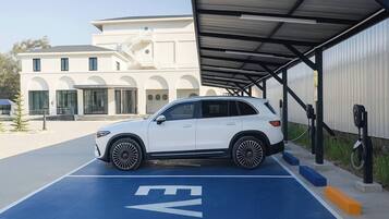 A white SUV parked at an EV charging station with a building in the background.