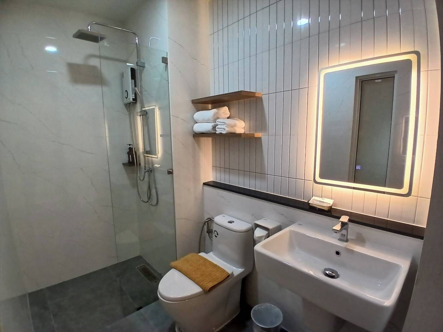 Ein modernes Badezimmer mit einer begehbaren Glasdusche, einer Toilette und einem Waschbecken mit Spiegel darüber.