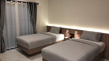 A hotel room with two beds, a nightstand with a phone, and a wall-mounted air conditioner.