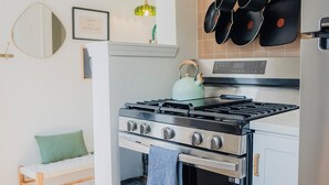 Eine Küche mit Herd, Backofen und hängenden Töpfen.