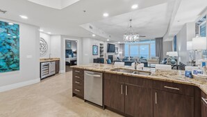A spacious kitchen with dark wood cabinets, a granite countertop, and a stainless steel dishwasher. - Turquoise C2508 (Orange Beach)
