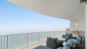 A balcony with a view of the sea, furnished with sofas and a table. - Turquoise C2508 (Orange Beach)