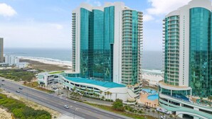 A modern hotel with a curved facade, multiple floors, and a pool area. - Turquoise C2508 (Orange Beach)