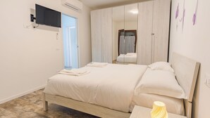 A bedroom with a bed, a bedside table, a mirror, and a TV mounted on the wall. - Lake Harmony Suite - One Bedroom Apartment, Sleeps 4 (Manerba del Garda)