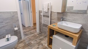 A modern bathroom with a white sink, wooden vanity, and a towel rack. - Lake Harmony Suite - One Bedroom Apartment, Sleeps 4 (Manerba del Garda)