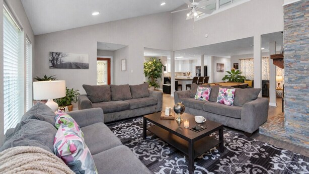 Ein geräumiger Wohnbereich mit zwei grauen Sofas, einem Couchtisch und einem gemusterten Teppich.