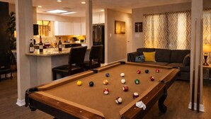 Ein Billardtisch in einem Wohnzimmer mit einer Bar im Hintergrund.