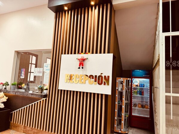 A reception area with a vertical wooden panel design, a reception desk, and a vending machine.