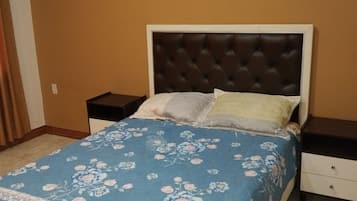 Un dormitorio con una cama, dos mesitas de noche y una pared con tres cuadros enmarcados.
