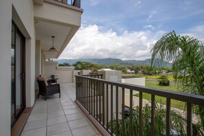 A balcony with a view of mountains, a dining area with chairs, and a railing. - Jaco Bay 4303 (Jacó)