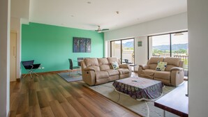 A spacious living room with two beige sofas, a coffee table, and a view of the outdoors through large windows. - Jaco Bay 4303 (Jacó)