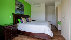 A bedroom with a bed, nightstands, a dresser, and a green wall. - Jaco Bay 4303 (Jacó)
