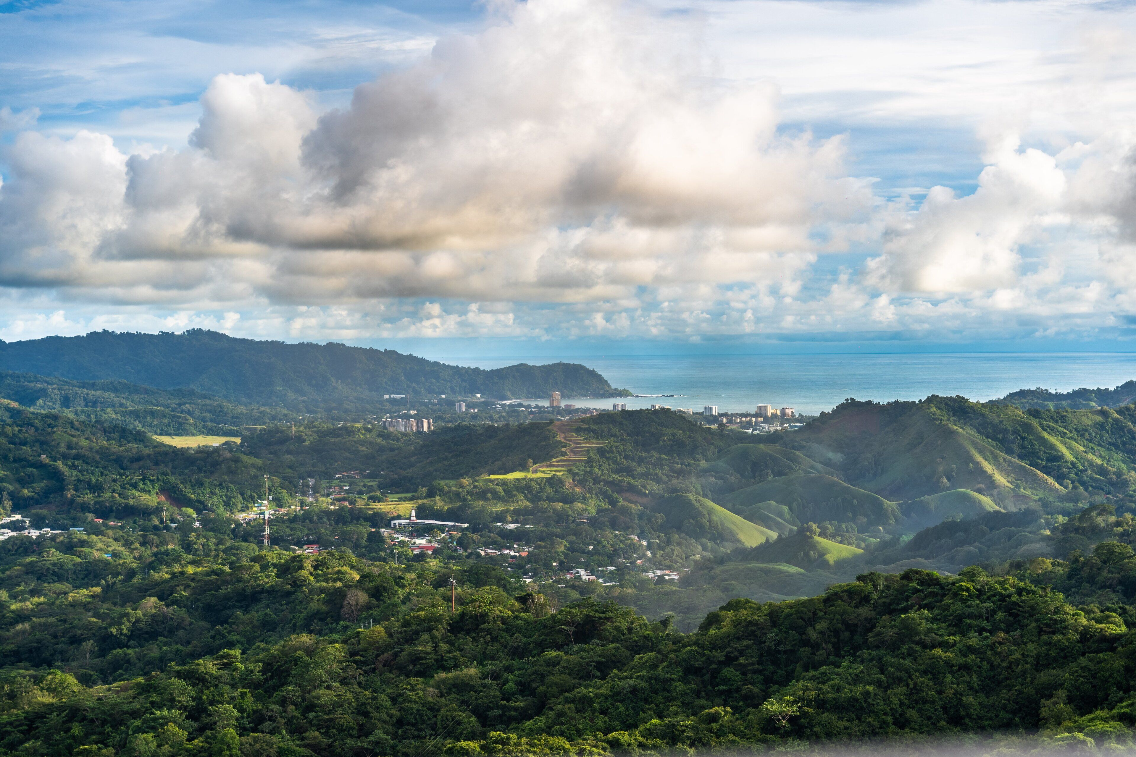 A mountainous landscape with a view of the sea and scattered buildings.