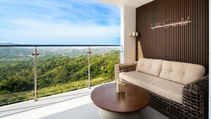 Ein Balkon mit Blick auf eine gebirgige Landschaft, ein Korbsessel und ein runder Couchtisch.
