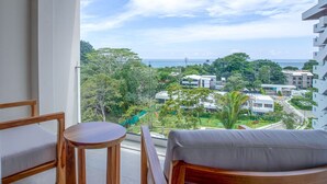 A balcony with a view of a coastal cityscape, including buildings and greenery. - Selva Coral 0701 (Jacó)