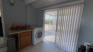 Ein Waschbereich mit Waschmaschine, Holzschrank und einer Arbeitsplatte mit Blumenarrangements.