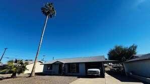 Ein Wohnhaus mit Garage, einer hohen Palme und blauem Himmel.