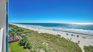 Een strand met een heldere lucht, een zandstrand en enkele parasols.