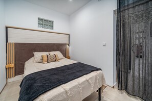 A bedroom with a bed, a window, and a door.