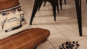 Un comedor con una mesa y sillas de madera, un tapete estampado con motivos de cebra, un sofá de cuero marrón y una escalera de madera.