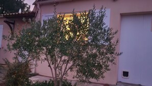A house with a pink exterior, a white door, and a window with a warm light.