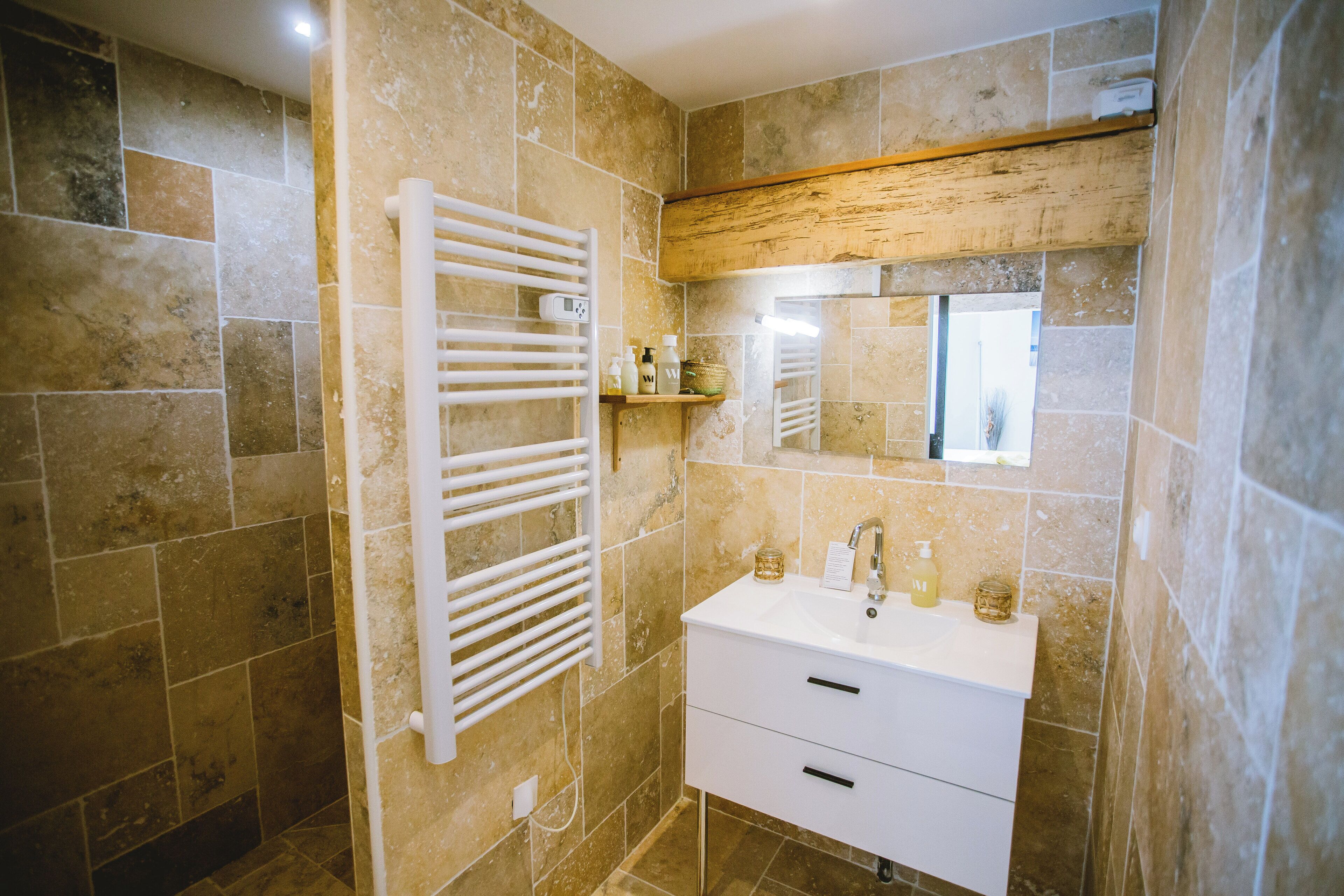 Un baño con un lavabo blanco, un espejo y un perchero para toallas.