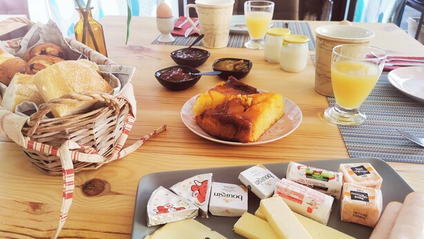A breakfast table with bread, pastries, a plate of fruit, condiments, and dairy products. - La Grange de Cablanc (Monestier)
