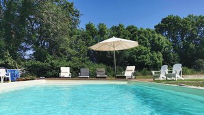 A clear swimming pool with white lounge chairs and an umbrella. - La Grange de Cablanc (Monestier)