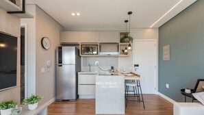 A modern kitchen with a central island, built-in appliances, and pendant lighting. - Charming Studio in Cambuí (Campinas)