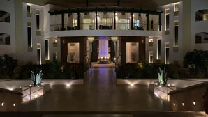 Ein modernes Hotel mit einem zentralen Atrium, mehreren Balkonen und einem hell erleuchteten Eingang.