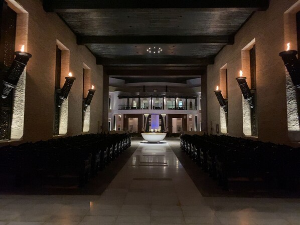 Un hall d’hôtel doté d’une fontaine centrale, de plusieurs rangées de sièges et d’une architecture moderne.