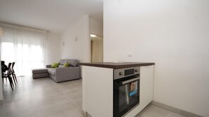 A modern kitchen with a built-in oven and a dining area with a sofa and chairs. - Residence Sandra three-room apartment Trilo for 6 persons (Rosolina Mare)