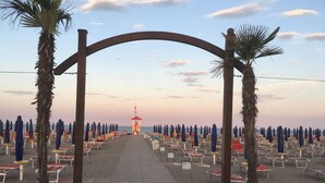 A beach with rows of umbrellas and sun loungers, a lifeguard tower, and a clear sky. - Residence Sandra three-room apartment Trilo for 6 persons (Rosolina Mare)