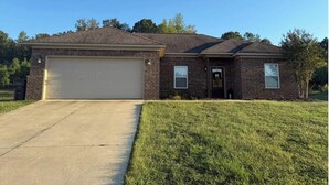 A two-story brick house with a garage, a front door, and a small front yard.