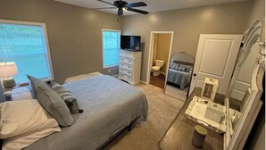 A bedroom with a bed, dresser, and a television.