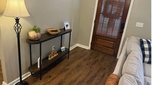 A hallway with a console table, a lamp, a basket, and a door with a window.