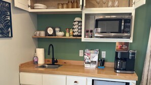 Une cuisine compacte équipée d’un four à micro-ondes, d’une machine à café et de placards de rangement.