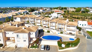 Quartiere residenziale con case dotate di tetti in tegole, una piscina e una vista aperta sul paesaggio circostante.