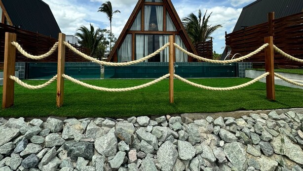 A triangular-roofed building with a glass facade, surrounded by a rope barrier and a stone-paved area. - LIMMAT CHALÉS (Presidente Juscelino)
