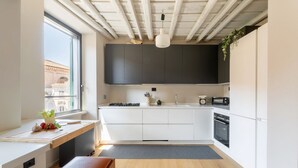 Une cuisine moderne avec des armoires blanches, un banc en bois, une fenêtre offrant une belle vue et un luminaire suspendu.