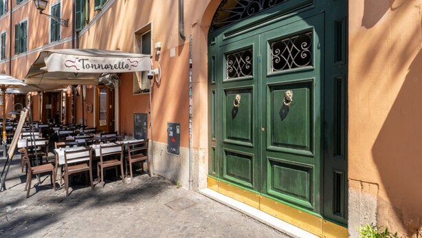 Un restaurant avec une terrasse, une porte verte et une enseigne indiquant « Tonnarello ».