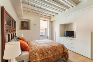 A bedroom with a bed, a TV, a window, and a ceiling with exposed beams. - Zenaria Trastevere, Zen Design in Heart of Rome (Rome)