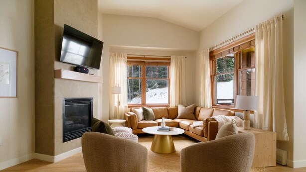 A modern living room with a fireplace, leather sofa, and a flat-screen TV mounted on the wall.
