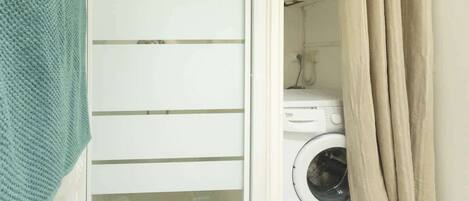 Een wasserette met een wasmachine en een droogrek.