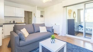Een moderne woonkamer met een grijze bank, een witte salontafel en een blauw vloerkleed.