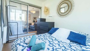 Een slaapkamer met een bed, een slaapbank, een spiegel en een schuifdeur naar een balkon.