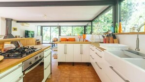 Een moderne keuken met een centraal eiland, witte kastjes en een groot raam voor natuurlijk licht.